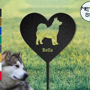 Puede incluir: Estaca de jard&iacute;n de metal negro en forma de coraz&oacute;n con una silueta de un perro y el nombre "Bella" inscrito. La estaca est&aacute; en un &aacute;rea cubierta de hierba.