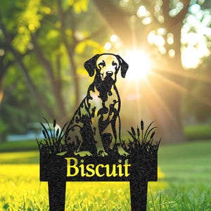 May include: Black metal silhouette of a Dalmatian dog sitting with the name "Biscuit" on a black metal sign. The sign is attached to a metal stake for inserting into the ground.