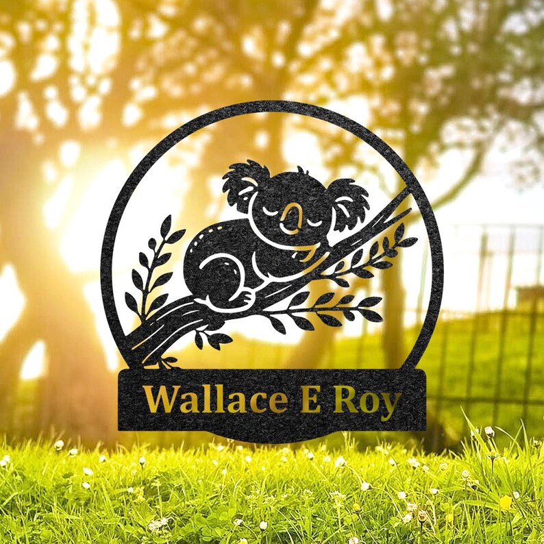 Pode incluir: Silhueta preta de metal de um coala dormindo em um galho com folhas. A silhueta est&aacute; em um c&iacute;rculo com o nome "Wallace E Roy" em uma faixa abaixo.