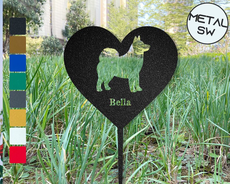 Puede incluir: Estaca de jard&iacute;n de metal negro en forma de coraz&oacute;n con una silueta de un perro y el nombre "Bella" inscrito debajo. La estaca est&aacute; en un &aacute;rea cubierta de hierba.