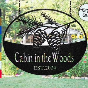 May include: Black metal oval sign with pine cones and branches, reading "Cabin in the Woods EST. 2024".
