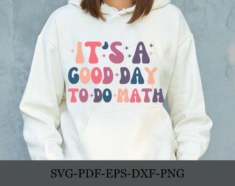Può includere: Una felpa bianca con il testo "IT'S A GOOD-DAY TO-DO-MATH" in lettere retrò colorate.