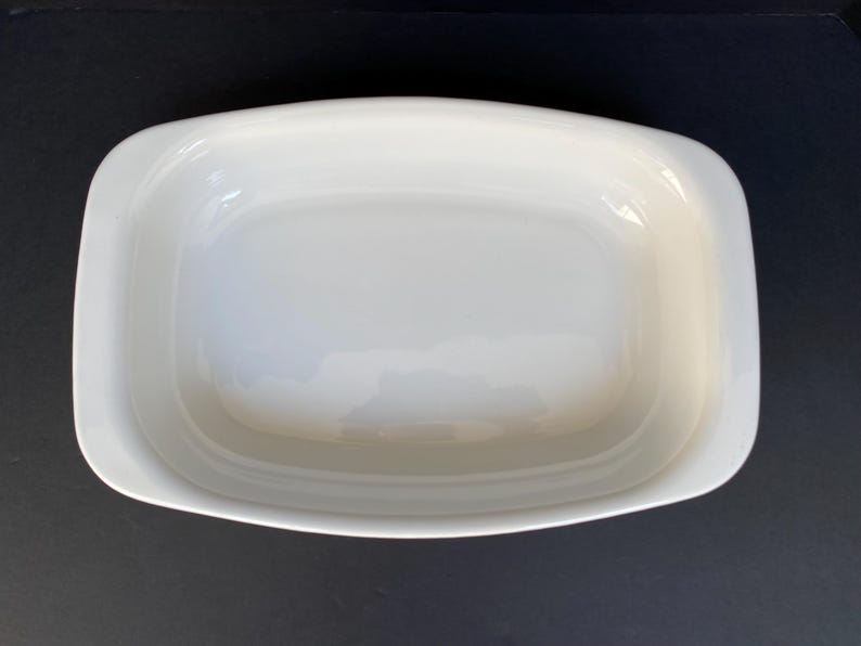 Może przedstawiać: Biała ceramiczna forma do pieczenia o prostokątnym kształcie i lekko zaokrąglonych krawędziach. Forma jest pusta i gotowa do pieczenia.