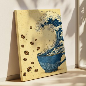 Könnte beinhalten: Ein rechteckiger Leinwanddruck mit einer blauen Kaffeetasse mit Wellenmuster. Eine große, stilisierte blaue Meereswelle steigt aus der Tasse auf, während dunkelbraune Kaffeebohnen auf der linken Seite vor einem hellgelben Hintergrund schweben.