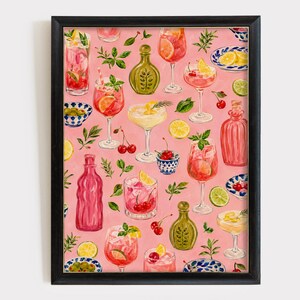 May include: A framed wall art print featuring a repeating pattern of watercolor cocktails, glass bottles, citrus slices, cherries, and small bowls of olives on a solid pink background. The artwork is encased in a simple black rectangular frame.