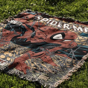 A Jacquard-woven blanket featuring a textured, intricate artwork woven into the fabric. The design showcases a stella comic design. The blanket appears thick and soft, suggesting it is both a decorative piece and a cozy item for warmth.