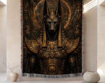 May include: A woven throw blanket featuring a detailed depiction of the Egyptian deity Anubis in shades of dark brown and gold. The design includes intricate armor, winged shoulder pieces, and a lotus flower emblem, finished with a fringed edge.