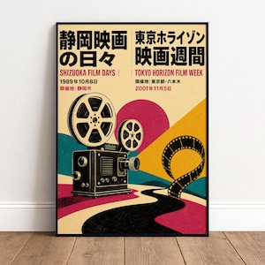 May include: A framed poster featuring a vintage film projector and a winding film strip. The design includes bold geometric shapes in pink, yellow, and teal, with Japanese and English text reading Shizuoka Film Days and Tokyo Horizon Film Week.