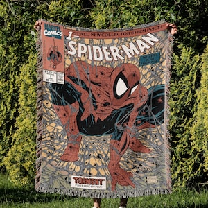 A Jacquard-woven blanket featuring a textured, intricate artwork woven into the fabric. The design showcases a stella comic design. The blanket appears thick and soft, suggesting it is both a decorative piece and a cozy item for warmth.