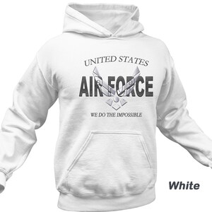 Może przedstawiać: Biała bluza z kapturem z napisem "United States Air Force" i logo Sił Powietrznych. Pod logo znajduje się napis "We do the impossible".