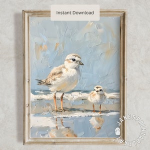May include: A painting of two white and brown shorebirds standing on a sandy beach with blue water reflecting the sky. The larger bird is standing in front of the smaller bird. The painting has a textured, brushstroke style.