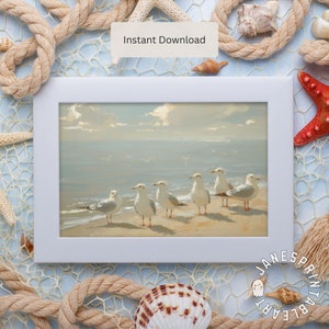 Op de afbeelding: Een ingelijst schilderij van een zeelandschap met zeven witte meeuwen die op een zandstrand staan. De lucht is lichtblauw met witte wolken. Het schilderij is in een witte lijst.
