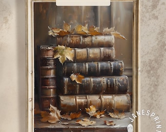Op de afbeelding: Een ingelijste print van een stapel oude boeken met gouden ruggen en versleten omslagen. Herfstbladeren liggen op de boeken. De tekst "Instant Download" staat bovenaan de afbeelding.