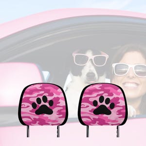 Può includere: Due poggiatesta per sedili auto rosa e neri con un design a forma di impronta di zampa. I poggiatesta sono realizzati in un tessuto morbido e soffice e sono progettati per fornire comfort e supporto ai passeggeri.