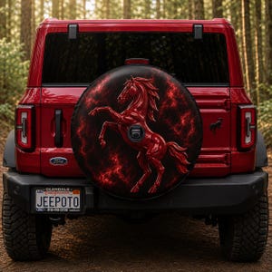 May include: A red Ford Bronco SUV featuring a circular spare tire cover with a graphic of a rearing red horse against a dark, fiery red and black nebula background. The vehicle has a California license plate that reads JEEPOTO and a Ford logo.