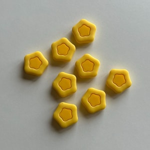 Peut inclure: Huit boutons jaunes en forme d'étoile avec une petite étoile jaune au centre.