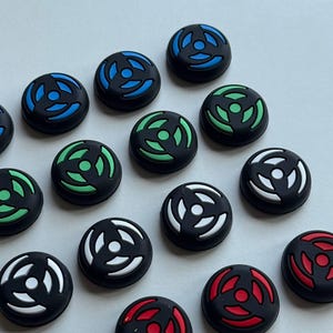Peut inclure: Un ensemble de capuchons de joystick noirs avec des motifs colorés. Les capuchons présentent un design circulaire avec des accents bleus, verts, blancs et rouges. Les capuchons sont en caoutchouc souple.