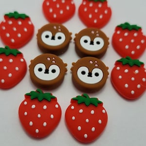 May include: Assortment of 10 colorful silicone buttons featuring a strawberry and a cartoon animal design. The buttons are red, brown, white, and green.