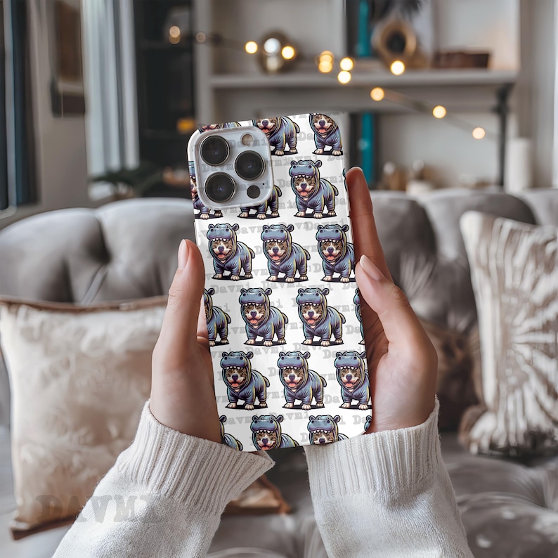 Puede incluir: Carcasa blanca para iPhone con un patr&oacute;n repetido de hipop&oacute;tamos de dibujos animados que llevan su&eacute;teres azules y blancos. Los hipop&oacute;tamos est&aacute;n todos mirando hacia adelante y tienen una expresi&oacute;n feliz. La carcasa tiene una lente de c&aacute;mara negra.