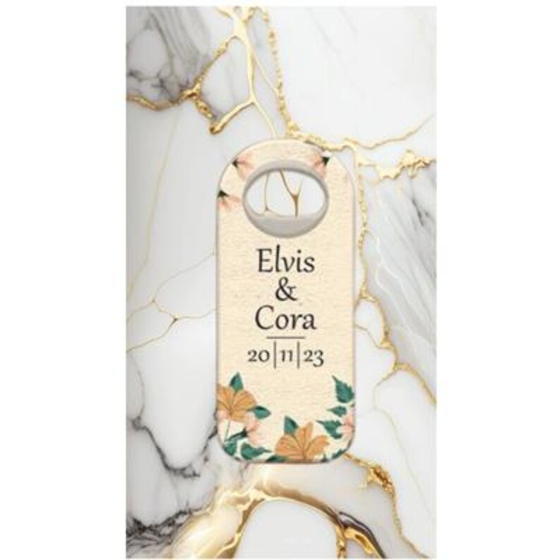 May include: A cream-colored door hanger with the names "Elvis & Cora" and the date "20/11/23" printed on it. The hanger features floral accents in peach and green, with a marble background.
