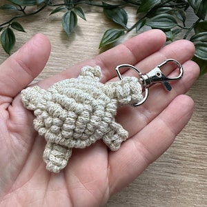 May include: A beige crocheted turtle keyring with a silver metal clasp.