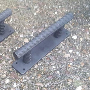 May include: Two black metal door handles with a rope-like design. The handles are mounted on a flat black metal plate.