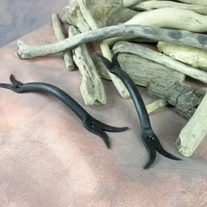 Peut inclure: Deux poignées de porte en métal noir avec un design incurvé unique. Les poignées ont une forme pointue en forme de griffe aux extrémités.