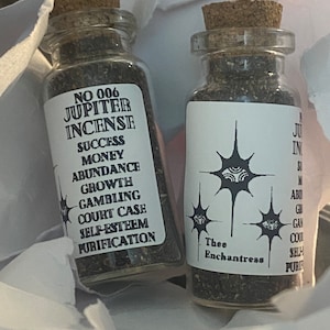 Puede incluir: Dos pequeños frascos de vidrio con tapas de corcho llenos de incienso marrón oscuro. La etiqueta del frasco de la izquierda dice "NO 006 JUPITER INCENSE SUCCESS MONEY ABUNDANCE GROWTH GAMBLING COURT CASE SELF-ESTEEM PURIFICATION". La etiqueta del frasco de la derecha dice "Thee Enchantress".