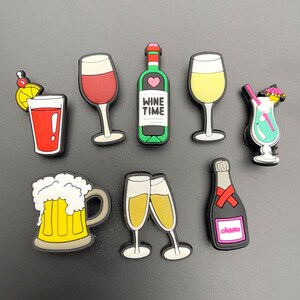 May include: A selection of drinks-themed charms. Includes a red cocktail, a red wine glass, a green wine bottle with "Wine Time" text, a yellow wine glass, a blue cocktail, a beer mug, two champagne flutes, and a champagne bottle.