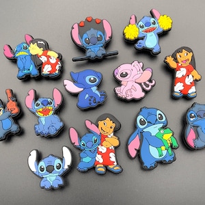 May include: A selection of colourful cartoon character charms, featuring blue and pink aliens, and a girl in a red dress. The charms have various poses and expressions. These charms are likely for shoes or accessories.