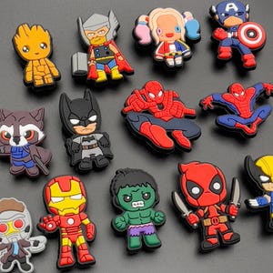 May include: A collection of colourful rubber shoe charms featuring various comic book characters including Groot, Thor, Harley Quinn, Captain America, Rocket Raccoon, Batman, Spider-Man, Iron Man, Hulk, Deadpool, Wolverine, and Star-Lord.