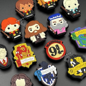 Könnte beinhalten: Eine Sammlung bunter Schuhanhänger aus Gummi mit verschiedenen Charakteren und Hauswappen aus der Harry-Potter-Reihe, darunter Gryffindor, Slytherin, Ravenclaw, Hufflepuff und ein rotes, rundes Platform 9 3/4 Schild mit schwarzem Text.