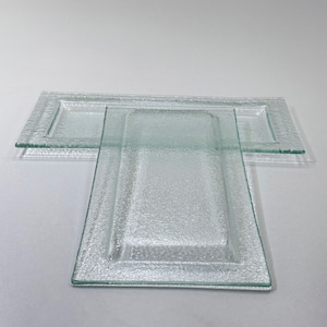 Könnte beinhalten: Zwei klare Glasservierplatten mit strukturierter Oberfläche. Die kleinere Platte ist in die größere Platte eingebettet.