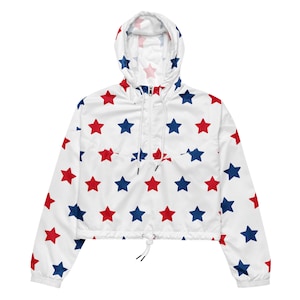 May include: A white cropped jacket with a drawstring waist and a hood. The jacket has a red and blue star pattern.