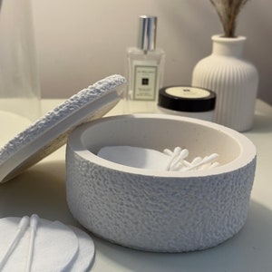 May include: White ceramic container with a textured surface, open to reveal cotton wool rounds and cotton buds inside. The container has a lid.