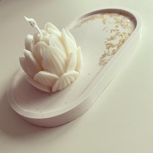 May include: A white ceramic tray with gold flecks and a white lotus flower candle in the centre.