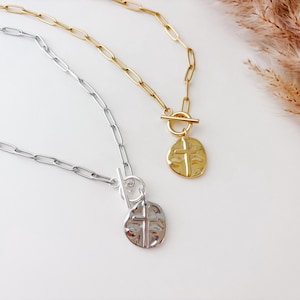 May include: Two silver and gold necklaces with a cross pendant. The necklaces have a toggle clasp and a chain link design.