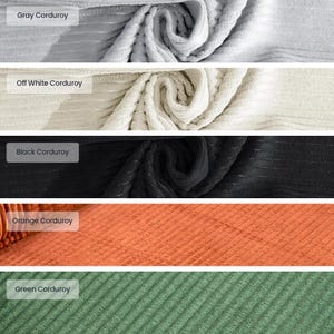 May include: A collection of corduroy fabric swatches in various colors. The swatches include gray, off-white, black, orange, and green. Each swatch has a label indicating its color. The corduroy has a ribbed texture.