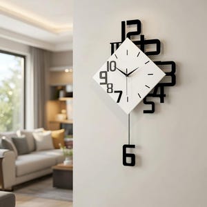 May include: Modern wall clock with a white square face and black hands. Black numbers are scattered around the face, with the number 6 hanging below. The clock is mounted on a light gray wall in a living room setting.
