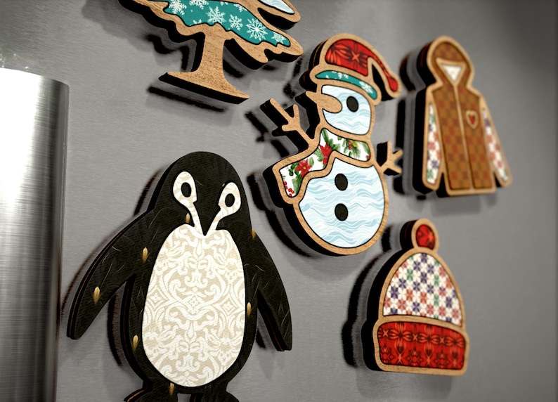 May include: A set of six wooden Christmas decorations featuring a penguin, snowman, winter hat, tree, and two winter jackets. The decorations are decorated with various patterns and colours, including red, green, blue, white, and brown.