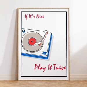 Könnte beinhalten: Ein gerahmter Druck mit einer Plattenspieler-Illustration. Das Kunstwerk hat einen weißen Hintergrund mit einem grau, rot und blau gestalteten Plattenspieler. Der Text "If It's Nice Play It Twice" ist rot geschrieben.