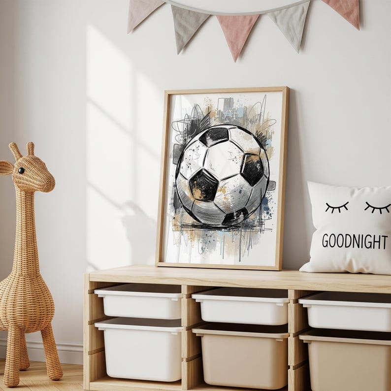 May include: A framed art print featuring a detailed sketch of a soccer ball. The black and white ball is set against a backdrop of abstract paint splatters in shades of gray, blue, and tan. The artwork is displayed in a light wood frame.