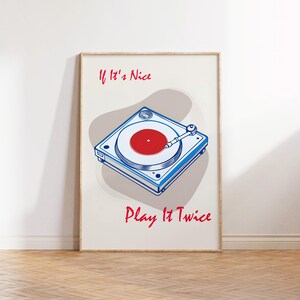Könnte beinhalten: Ein weißer Poster mit einer blauen und roten Illustration eines Plattenspielers mit dem Text "If It's Nice Play It Twice" in Rot.