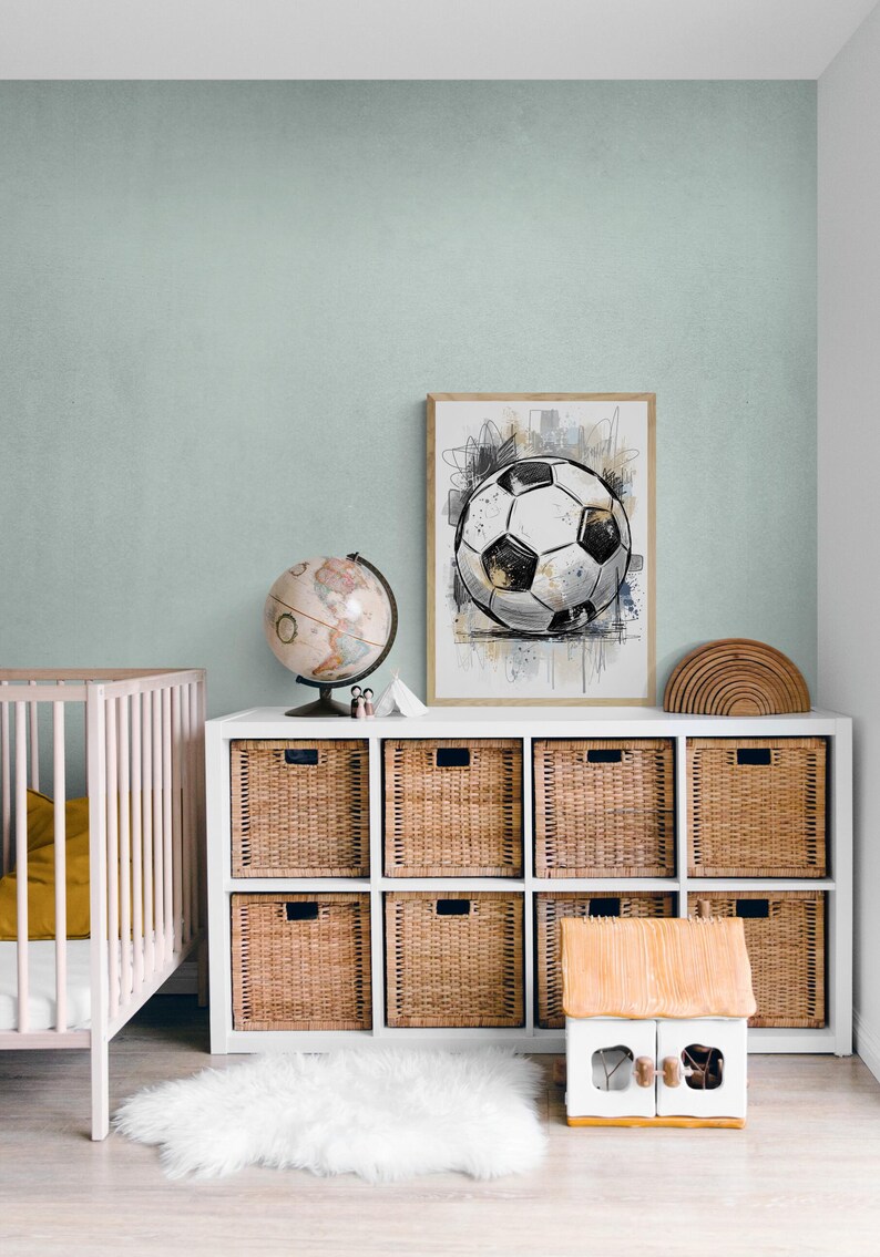 May include: A framed art print of a soccer ball in a child's room. The artwork is in black, white, and gold tones, with abstract background elements. The room features a white storage unit with woven baskets, a globe, and a small wooden house.