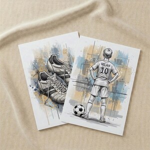 May include: Two art prints featuring soccer-themed illustrations. One print shows a pair of soccer cleats, while the other depicts a soccer player with the name "Milan" and the number "10" on the jersey, standing near a soccer ball.
