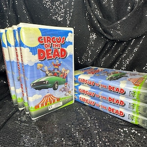 May include: A stack of five VHS tapes of the movie "Circus of the Dead". The tapes are all in a black and white color scheme with a cartoon image of a circus tent and a car with clowns on it. The text "Circus of the Dead" is in red and white letters.