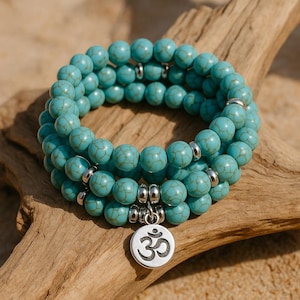 May include: Three turquoise beaded bracelets with silver accents and a charm featuring the Om symbol. The bracelets are made of round, light blue beads with a marbled effect. The bracelets are displayed on a piece of driftwood.