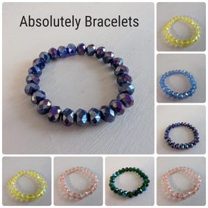 May include: Assortment of bracelets made with faceted glass beads in various colors, including blue, green, pink, and yellow. The bracelets are all elastic and have a simple design.
