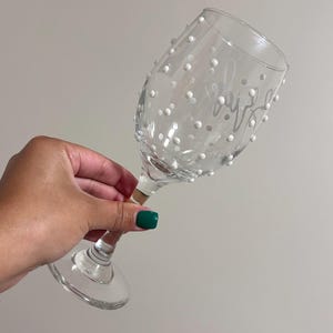 May include: A clear glass wine glass with white polka dots and the word "Cheers" etched on the side.