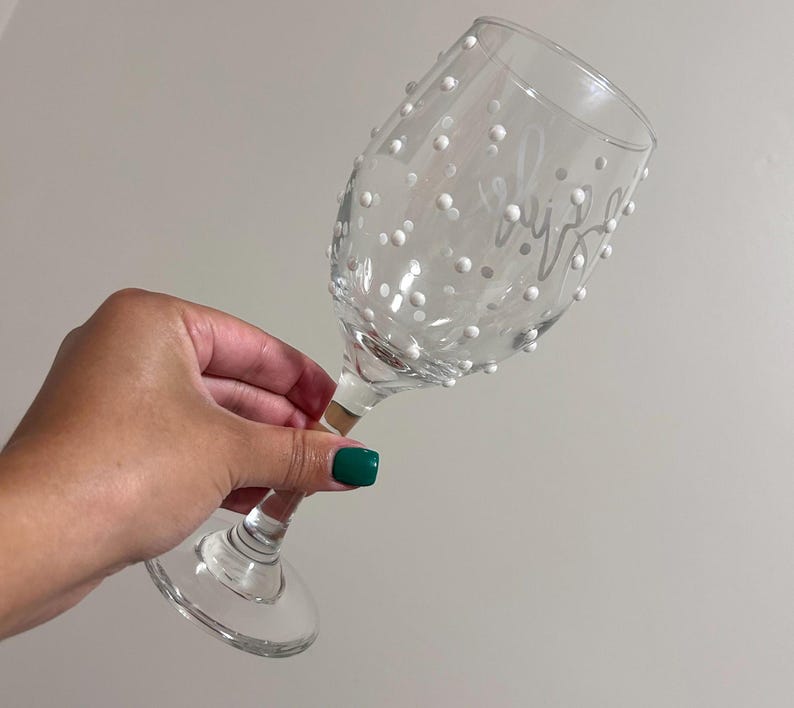 May include: A clear glass wine glass with white polka dots and the word "Cheers" etched on the side.